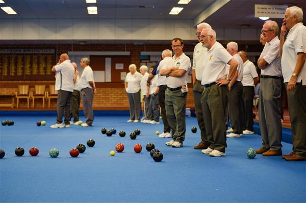 Players in club whites gather at the head to see which bowls are closest to the jack.