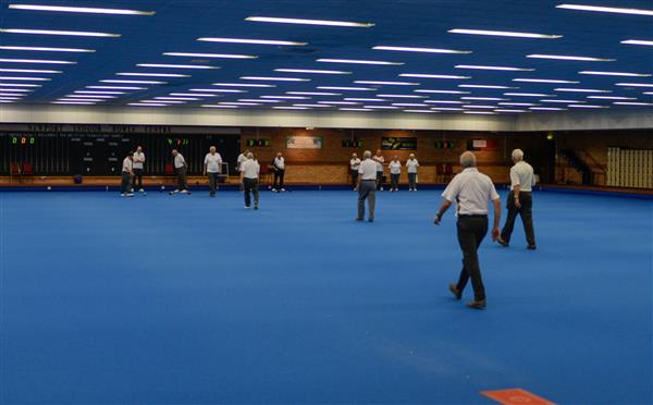 Games in play across the rinks of the main hall, under rows of ceiling lights.